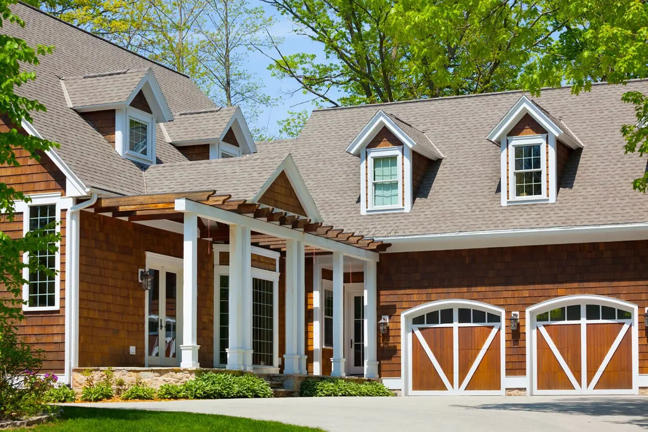 Beautiful residential home with professional brown asphalt shingle roofing, cedar shake siding, and elegant architectural details